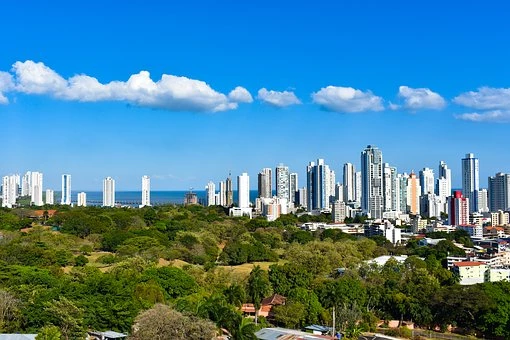 A view across Panama City with tall high rise buildings and blue sky with a stream of small clouds