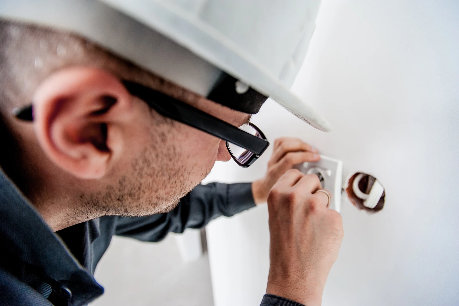 An electrician working on some wiring in a wall in a house