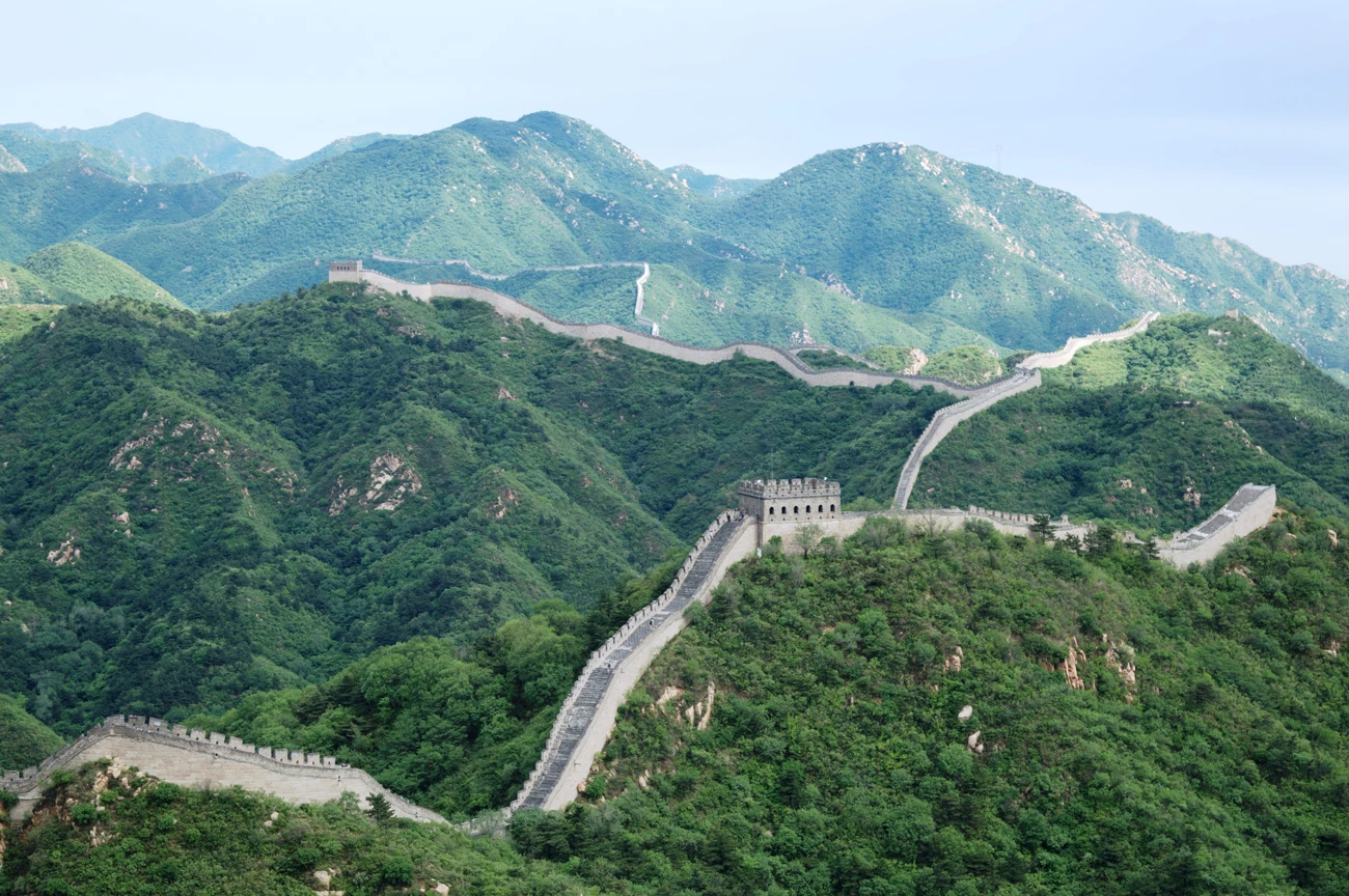 A view across rolling green hills in China with the Great Wall stretching off into the distance