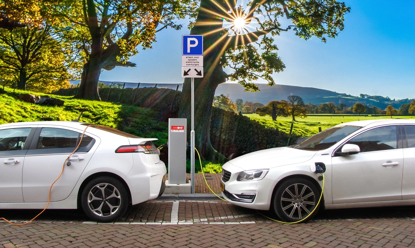 Two electric cars charging at a charge point on a sunny day