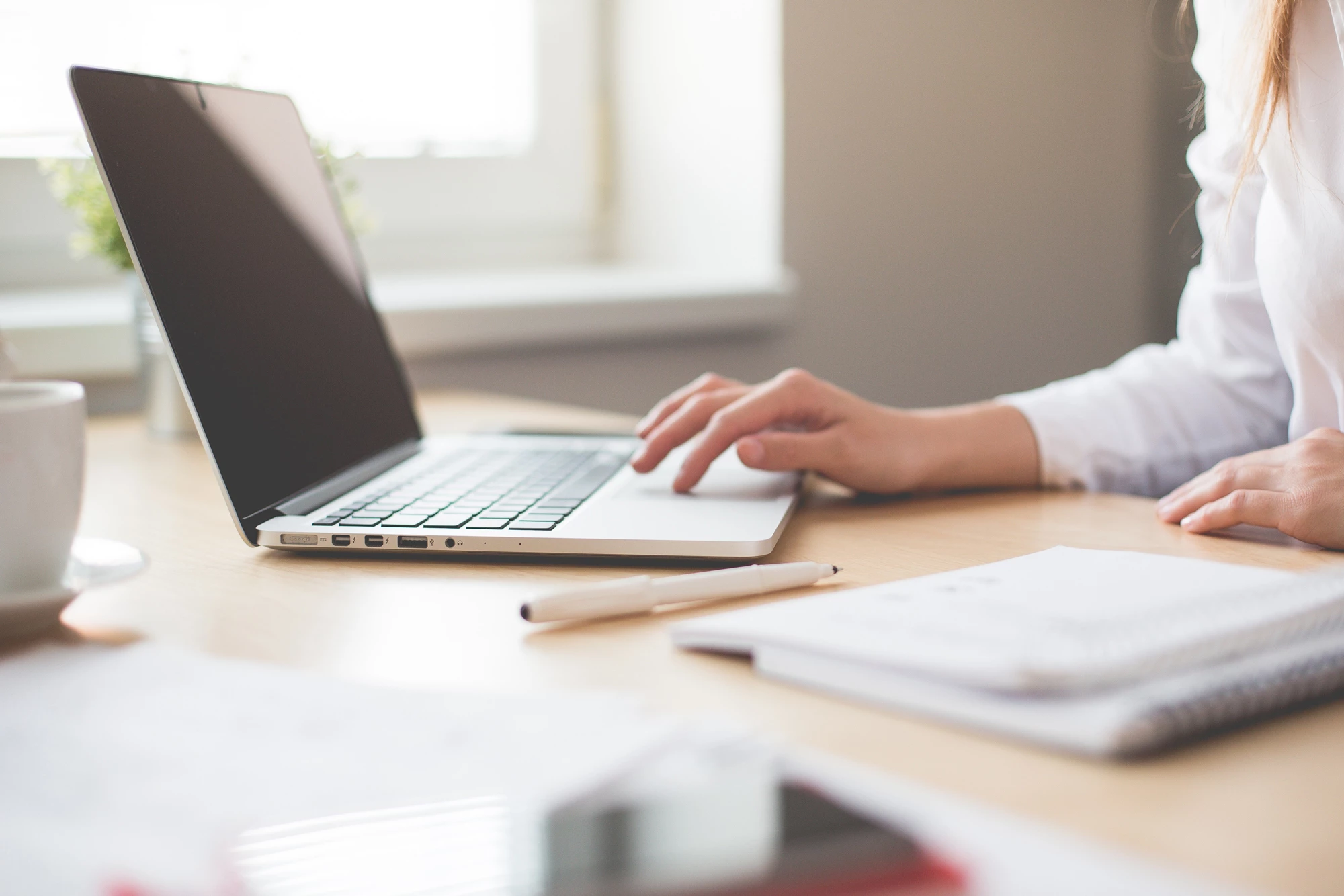 A person sitting at a desk in their home working on a laptop