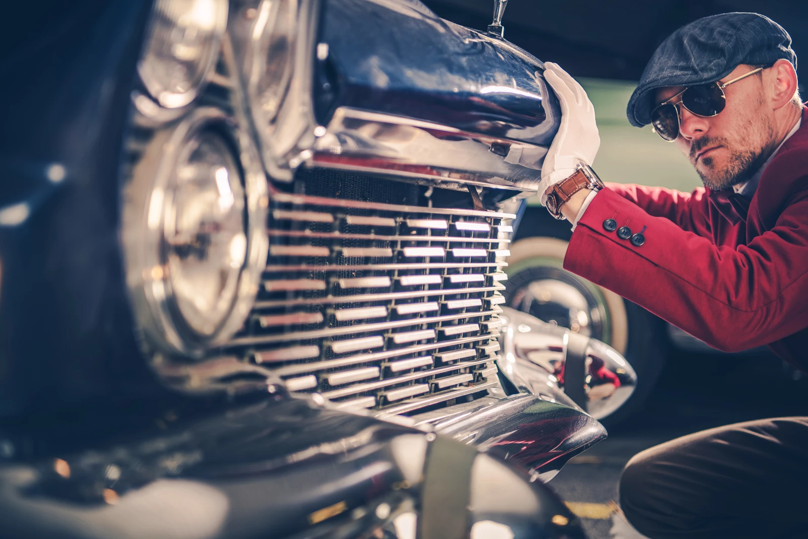 A vintage car restorer inspecting the front of a classic car