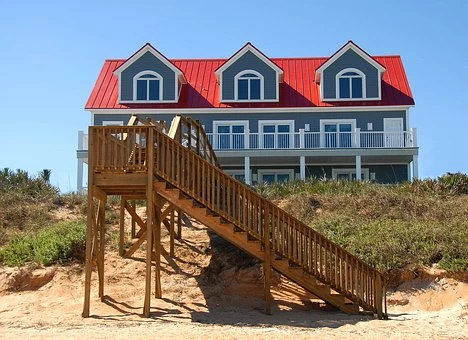 Large house on sandy beach front with wooden stairs leading down to the beach