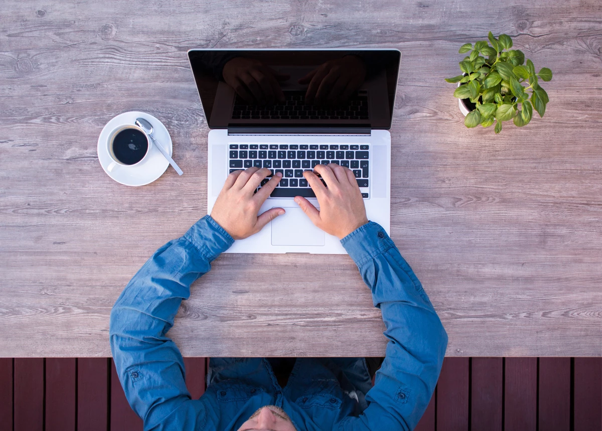 A man browsing on his laptop at a clean desk