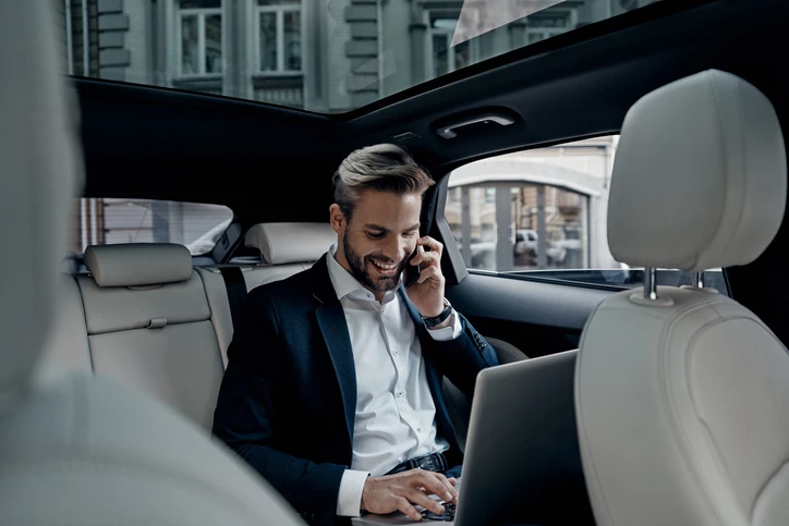 A businessman on his phone in the back of a car