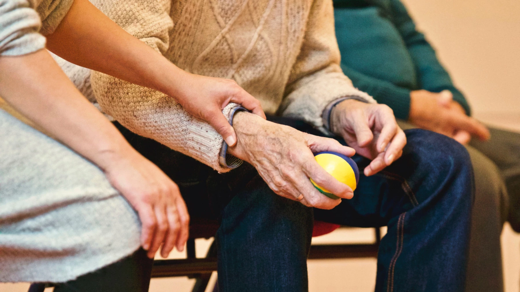 A care home worker helping a patient holding a stress ball