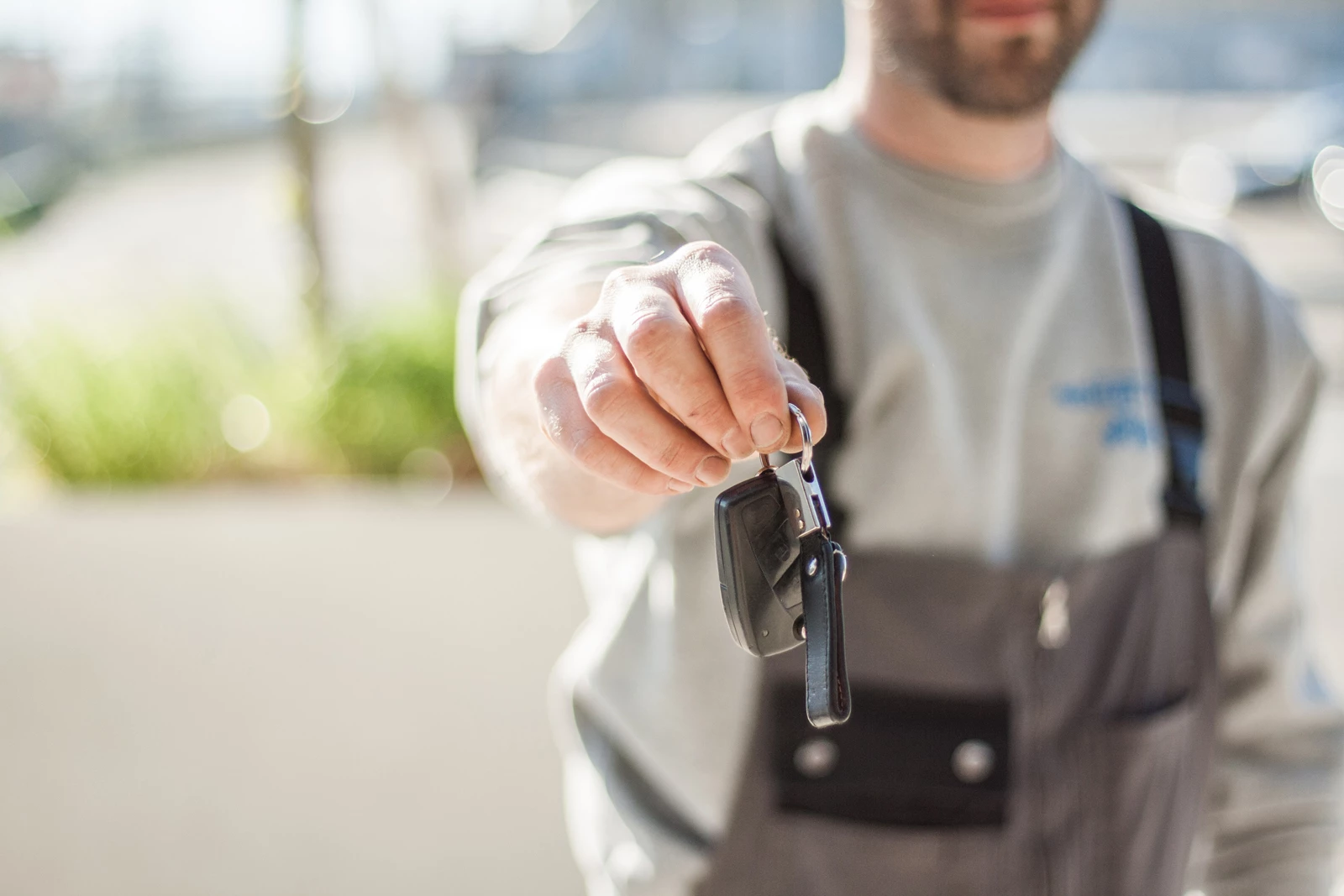 A mechanic handing the keys to a car over 