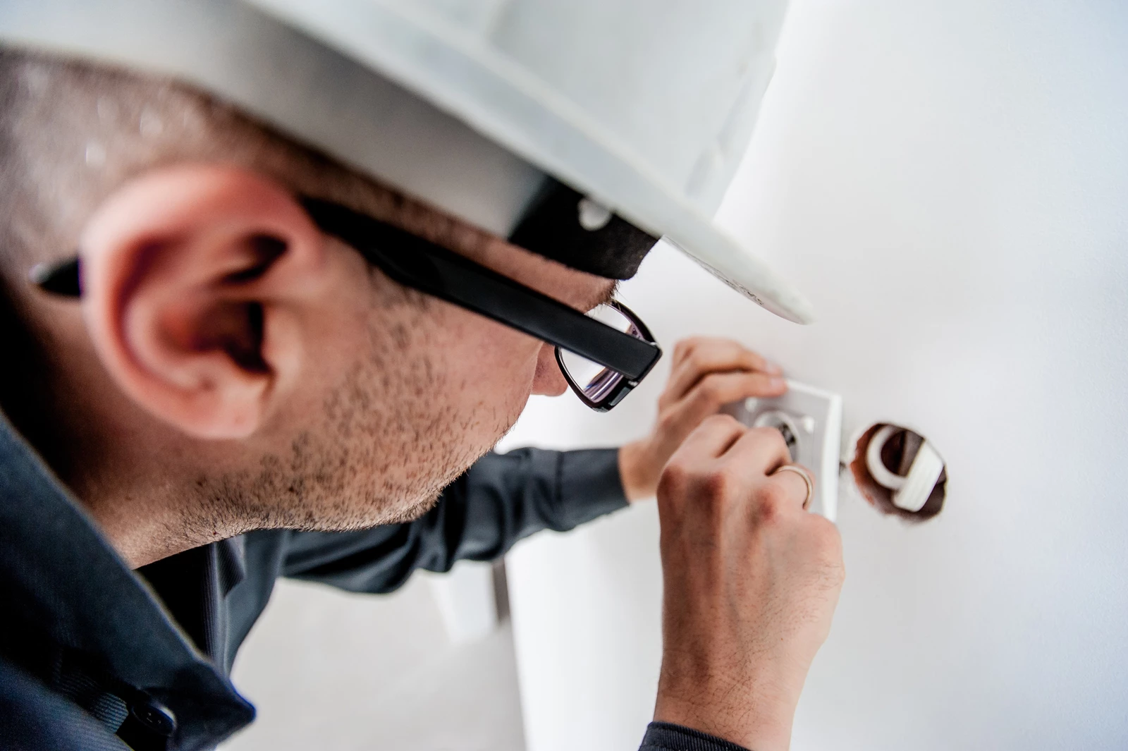 An electrician installing a plug into a wall