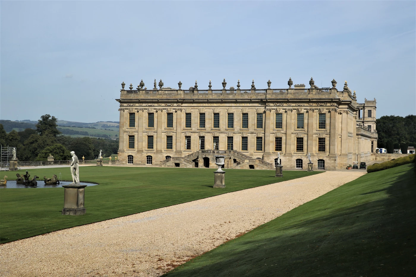 A vast manor house surrounded by pristine grassy gardens 