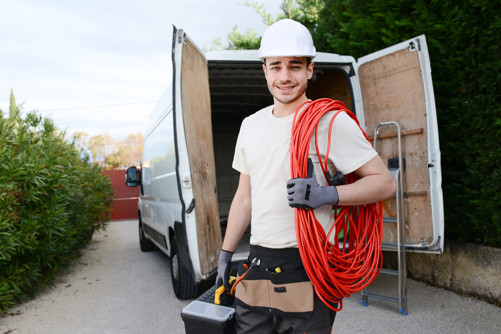 An electrician holding electrical equipment in-front of his van