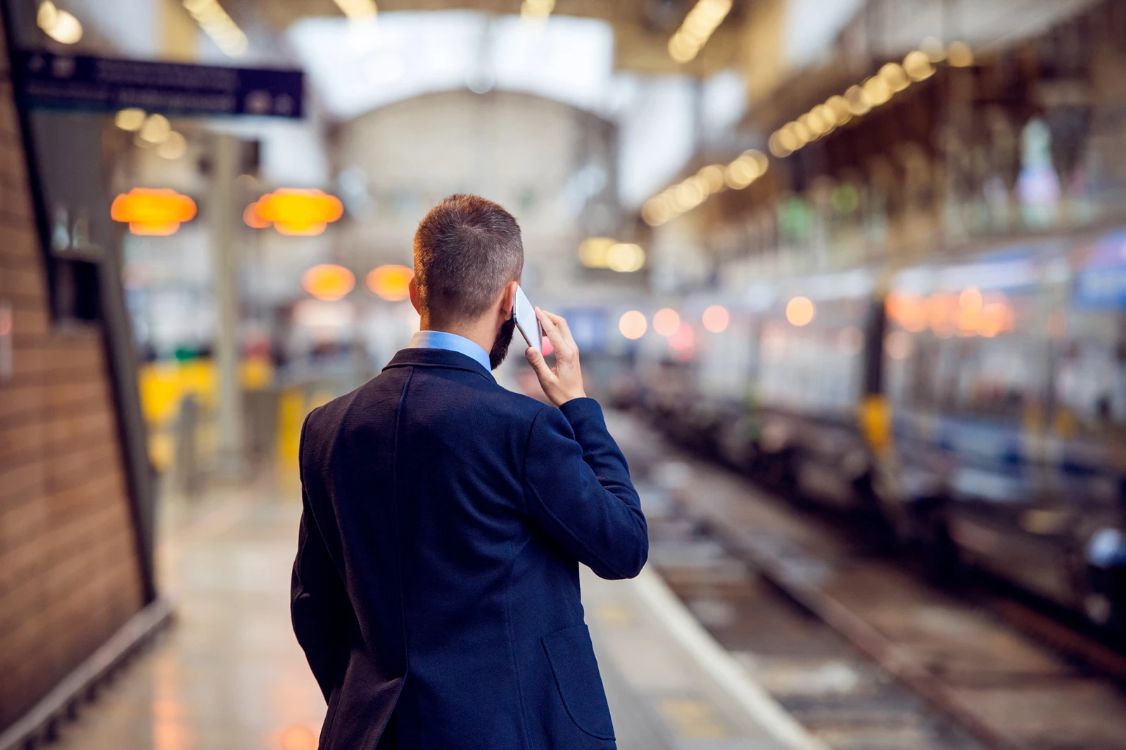 Business man on phone standing at train station