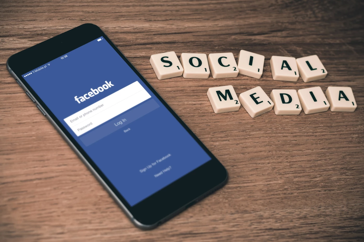 A mobile phone with the Facebook login screen on it next to scrabble tiles spelling out social media
