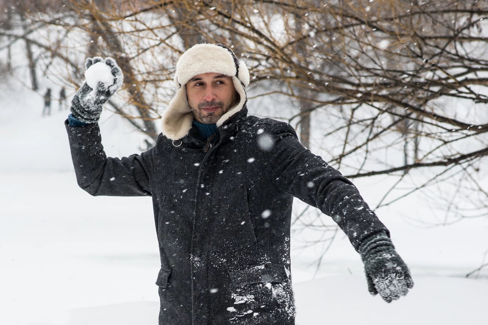 A man in winter clothes throwing a snowball
