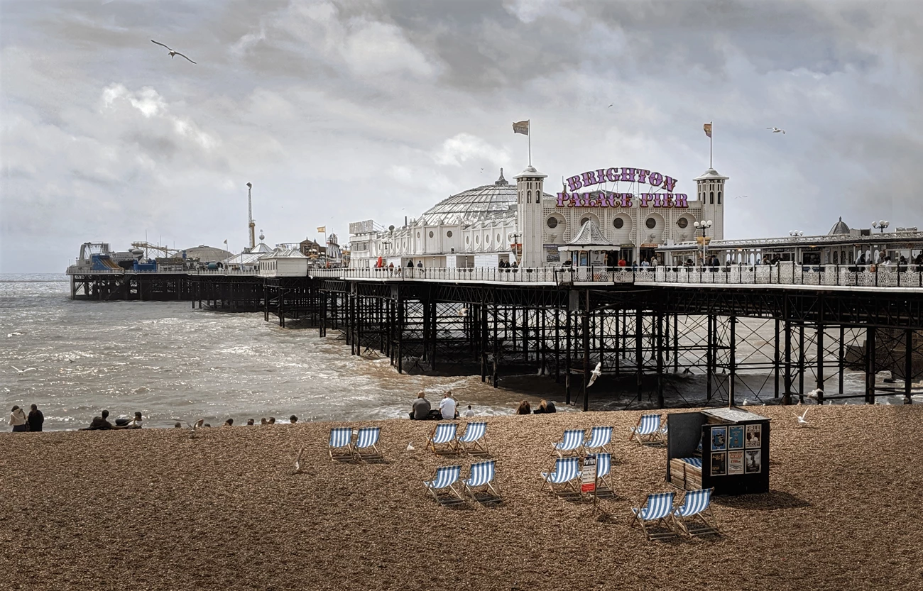 Brighton Palace pier on a pebbly beach looking out to sea on a cloudy day 