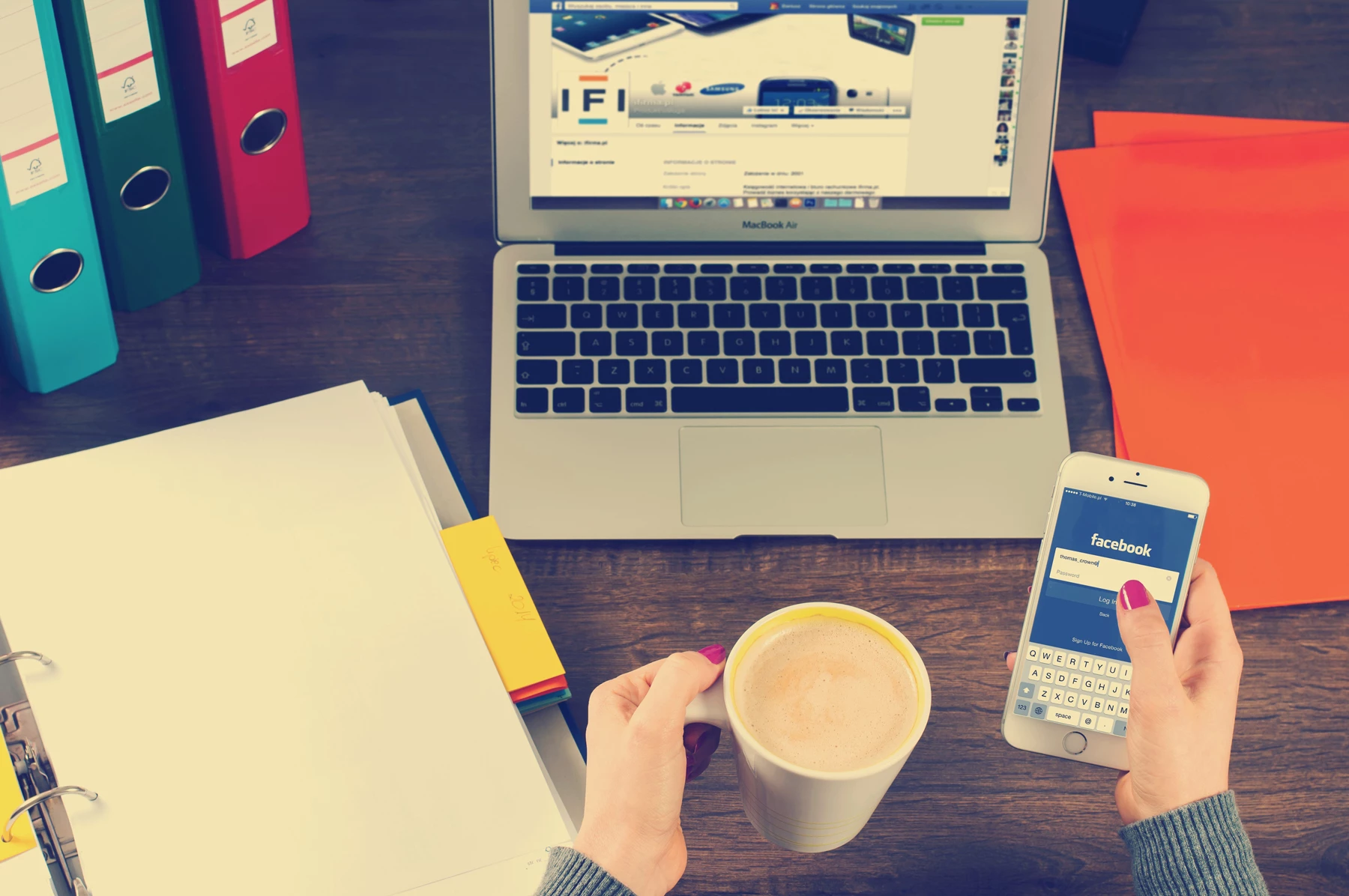 A hotelier using a laptop and phone at their desk signing up to social media