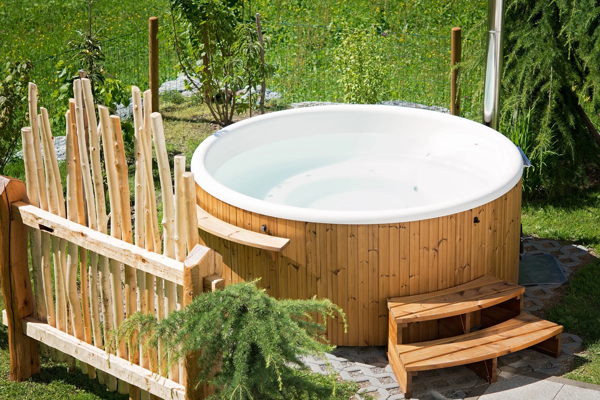 A hot tub in a garden with a wooden privacy fence in-front
