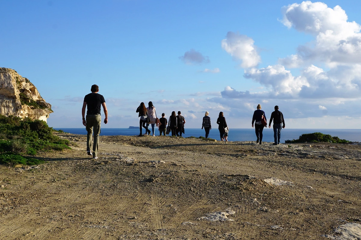 A shore excursion group walking along a ridge overlooking the sea