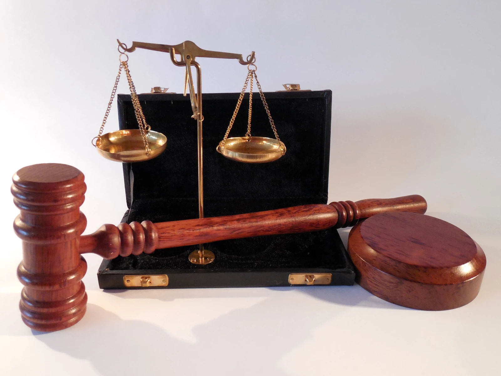 A judges gavel and scales with a case on a table