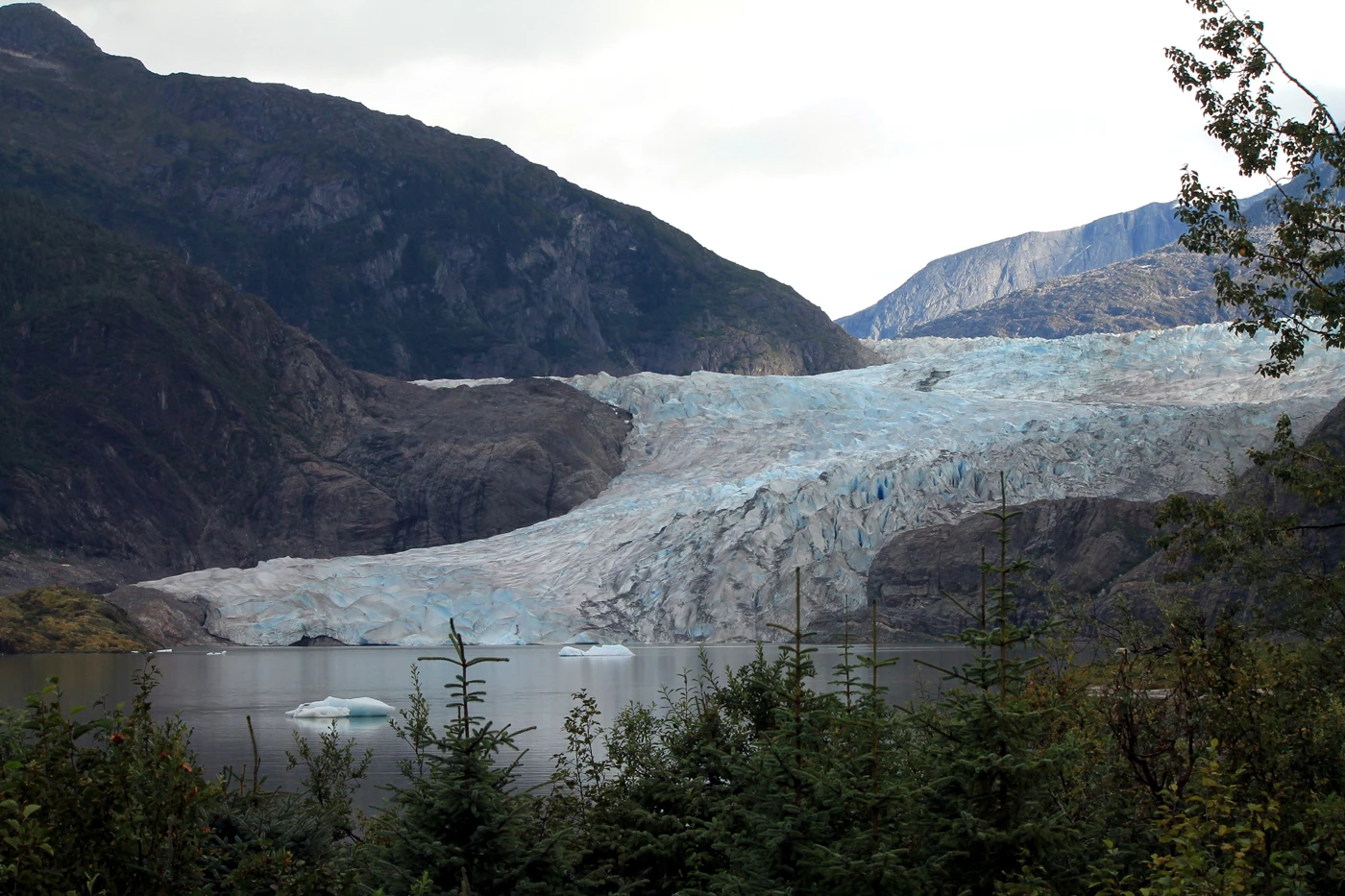The Mendenhall Glacier spilling out between mountains into a lake below