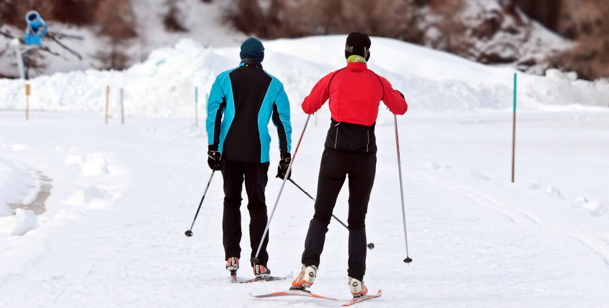 Two cross country skiers heading down a piste 