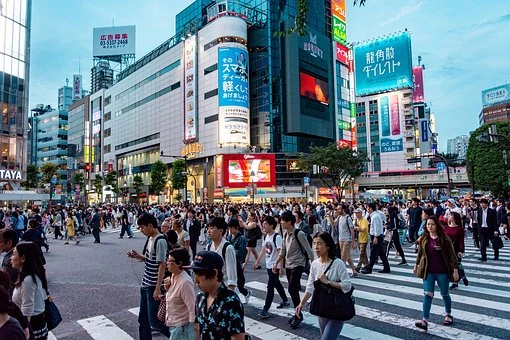 A busy crossing in front of tall, lit up buildings in Tokyo, Japan 