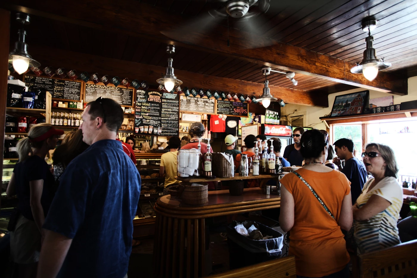 A busy pub with people standing around the bar