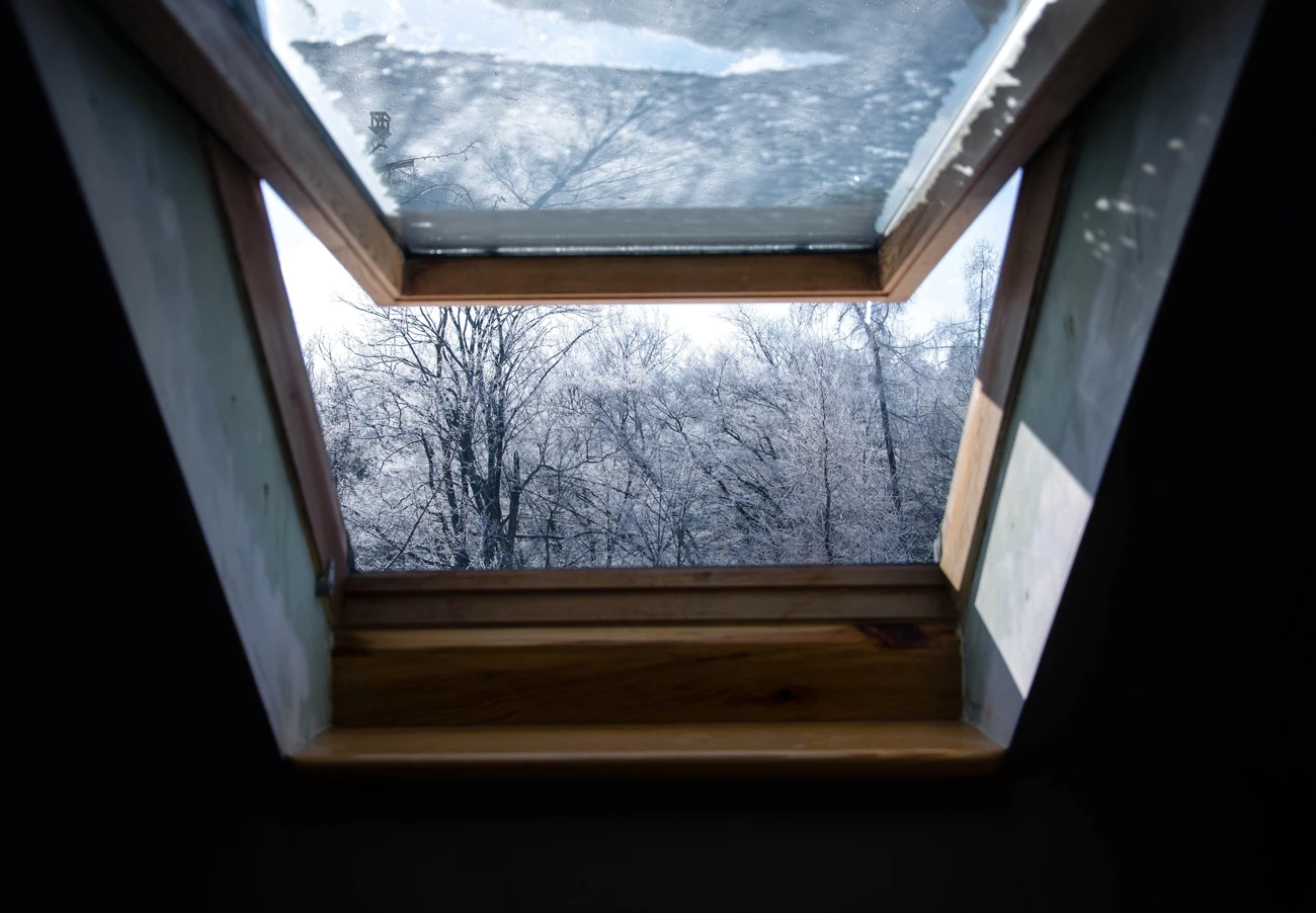 A skylight window opened on a house looking out to the winter weather