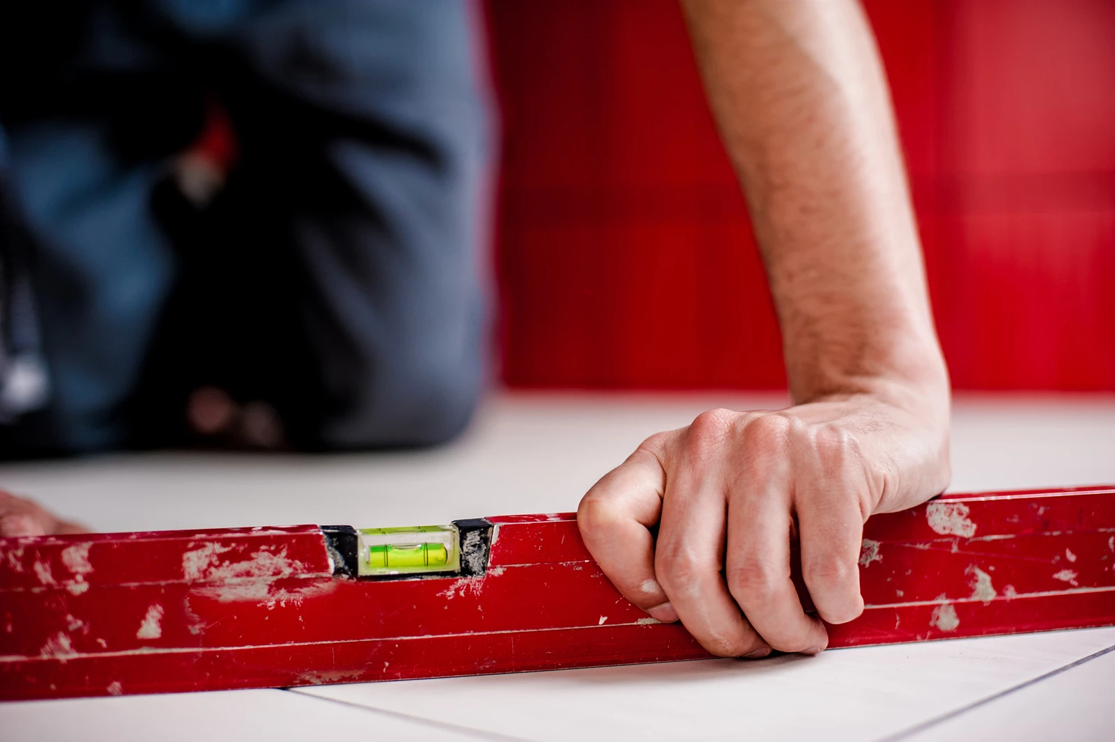 A construction worker using a large spirit level tool on the floor