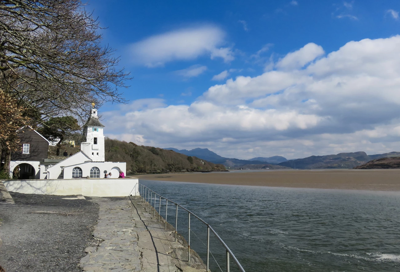 A white building next to a body of water with rolling mountains in the distance