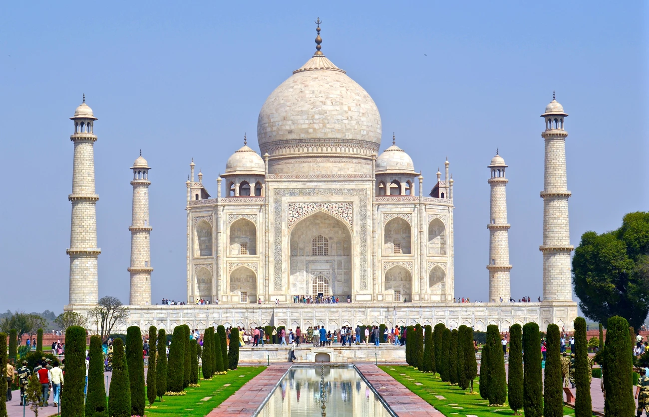 A view of the Taj Mahal on a sunny day with hundreds of people outside it