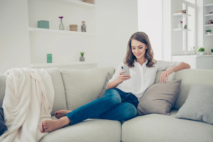 A woman sitting on a sofa reading her phone