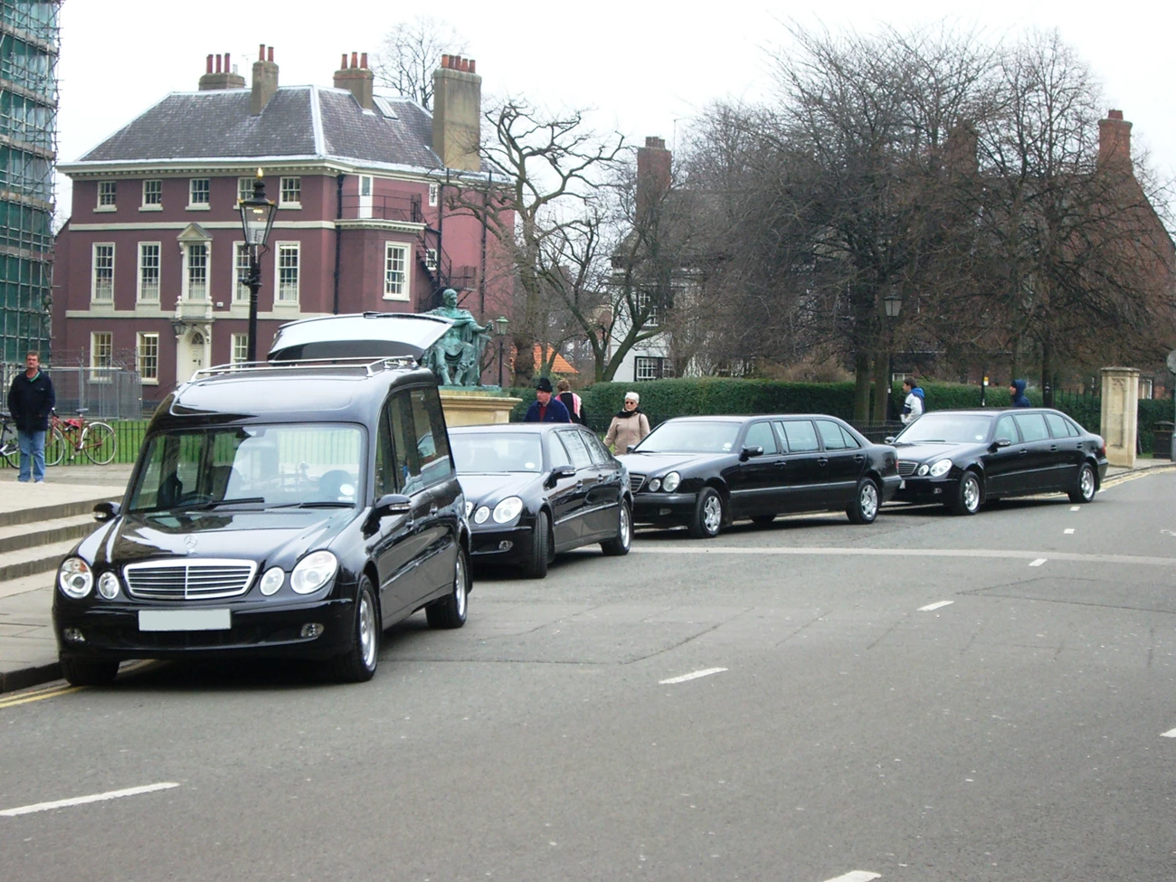 Funeral cars parked in a line outside of a funeral