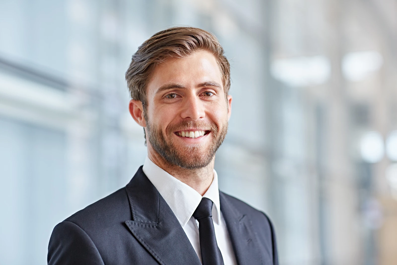 A smiling businessman smartly dressed in a suit in a modern building