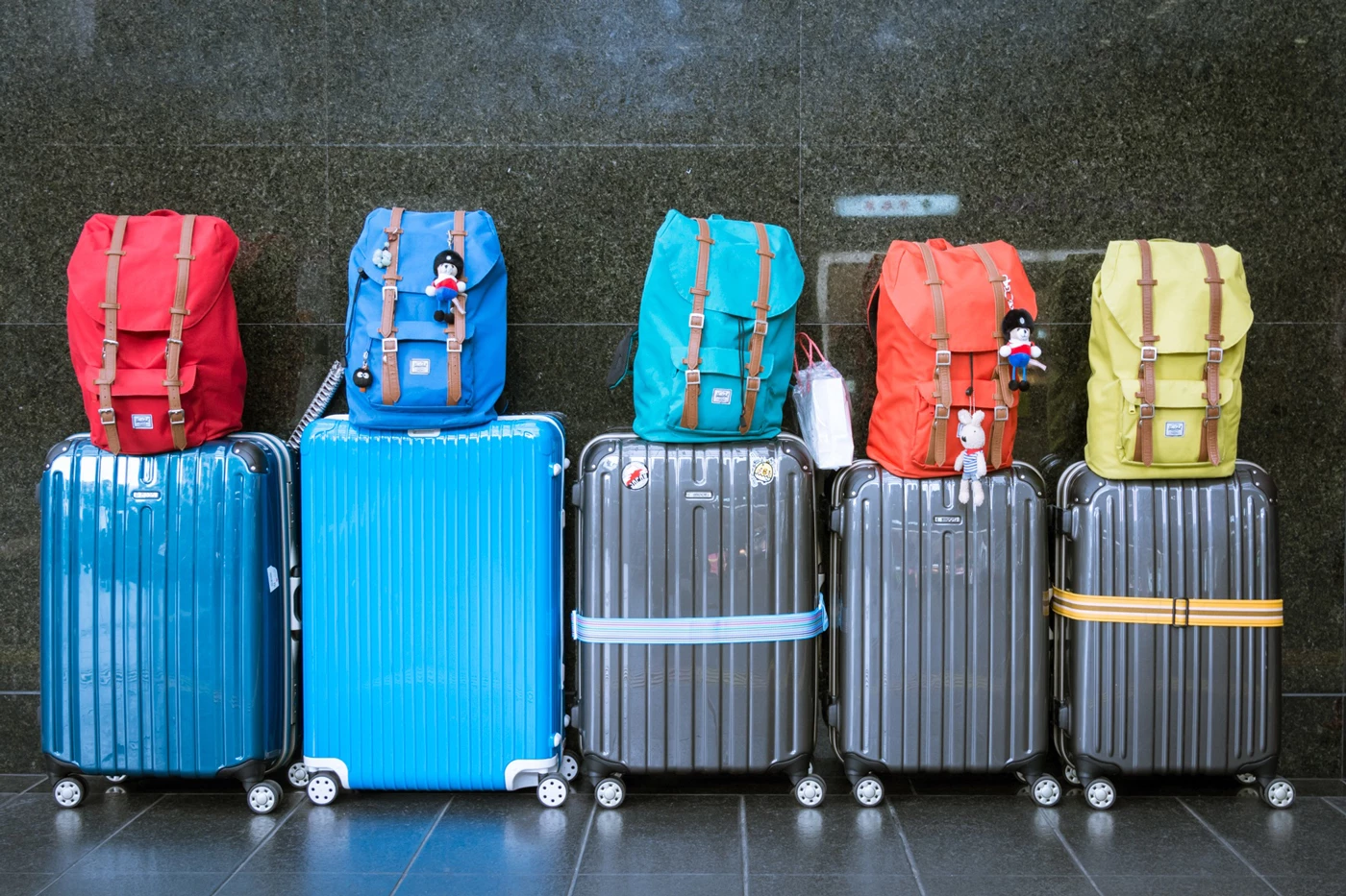 Various suitcases lined up against a wall with matching bags on top