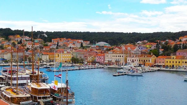 A blue watered bay with colourful buildings and small wooden boats 