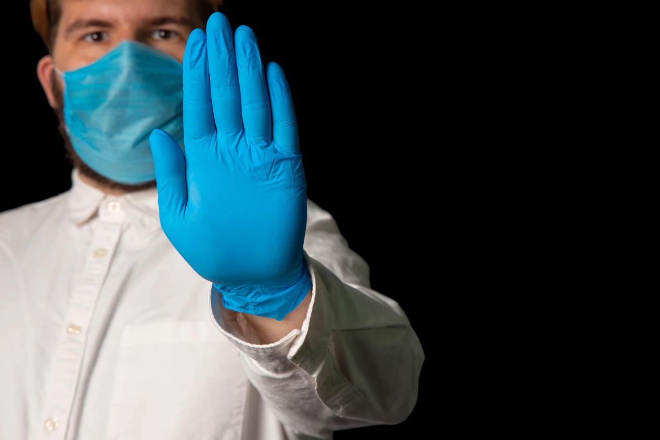 A man wearing a mask raising his hand with a glove on