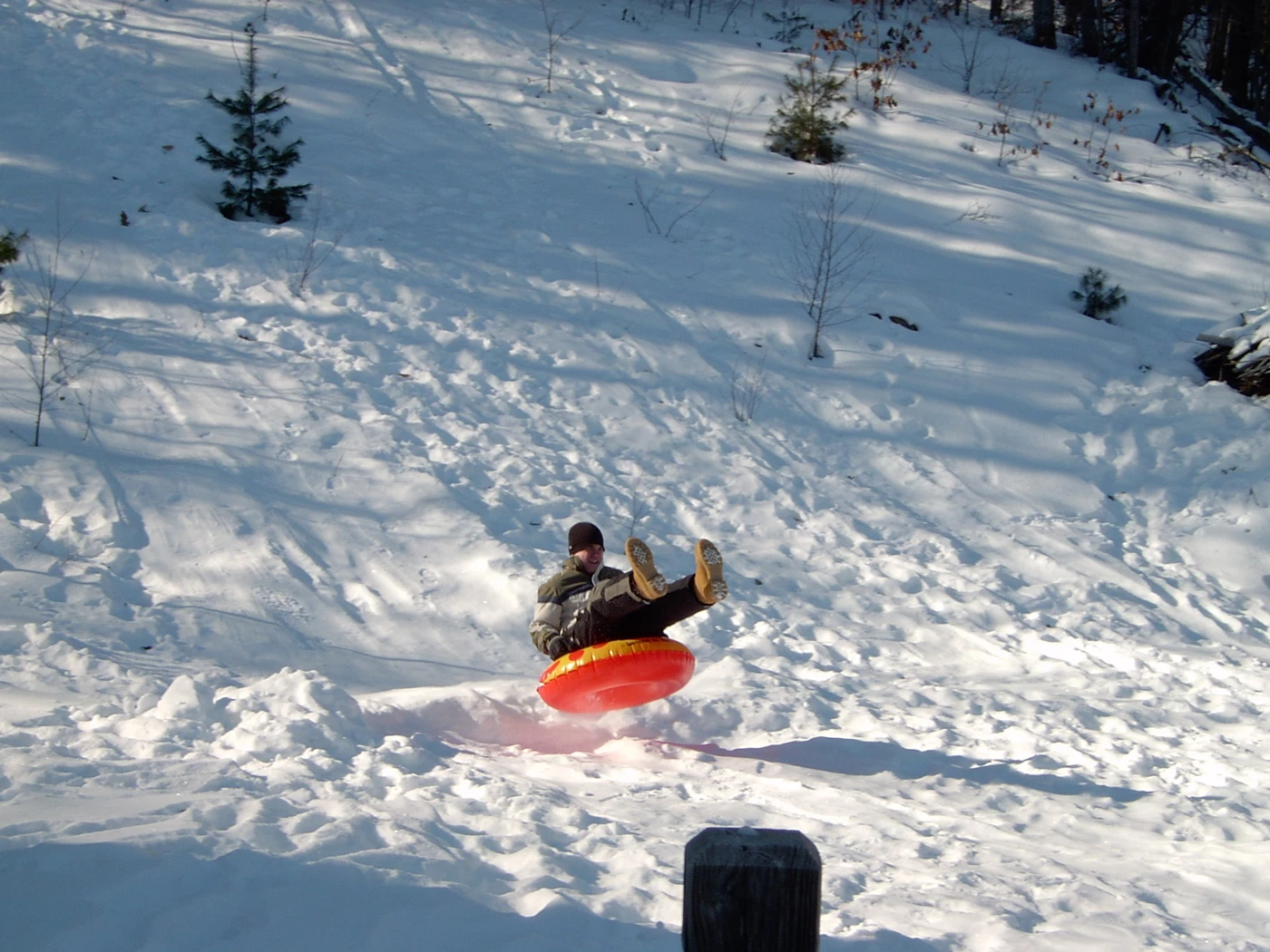 A man in the air coming off a snow ramp on an inflatable tube at the bottom of a slope