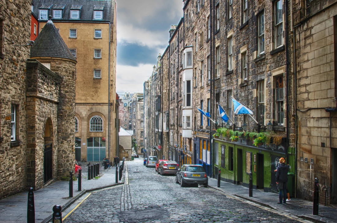 A narrow street between tall stone buildings on a gloomy day in Edinburgh