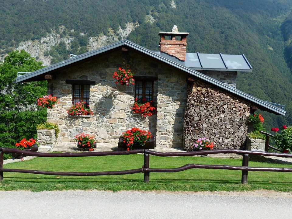 A stone holiday home decorated with red flowers