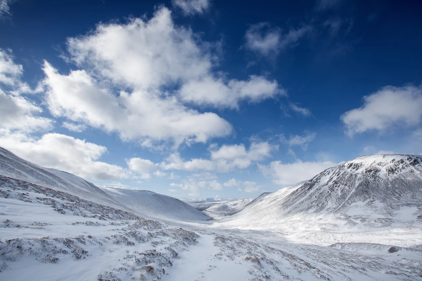 Tall snowy peaks under a cloud littered blue sky in the Scottish Highlands