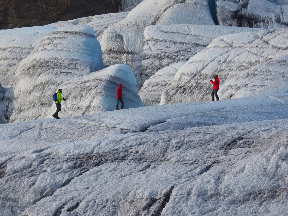 Three men in ski clothes walking along a glacier in Iceland