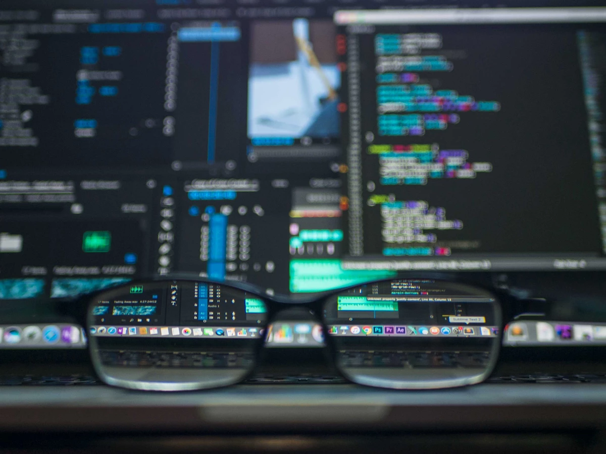 A pair of glasses in-front of a computer with code on it's screen