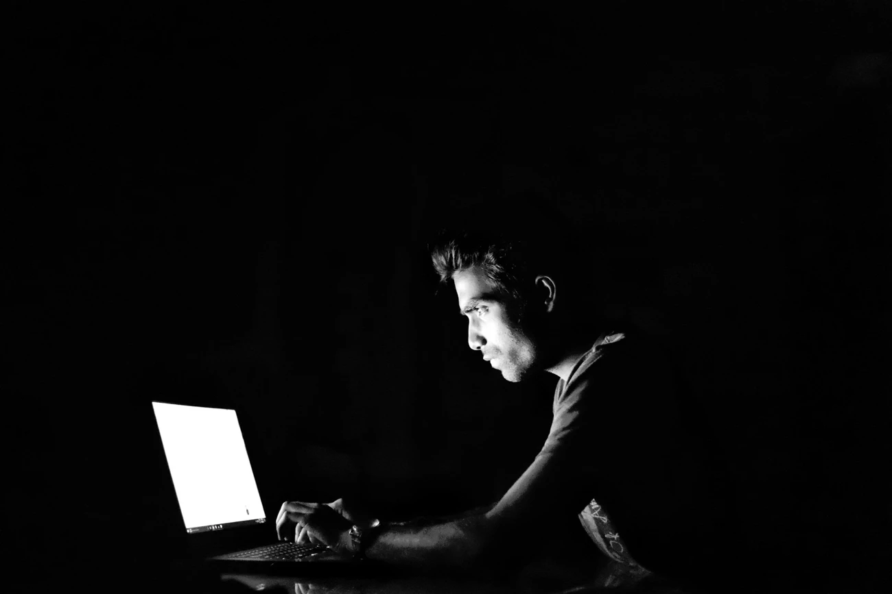 A hacker using a laptop in a darkrom