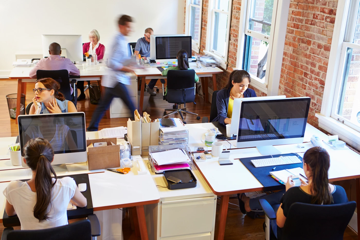 A busy office with workers sitting at their desks and moving around