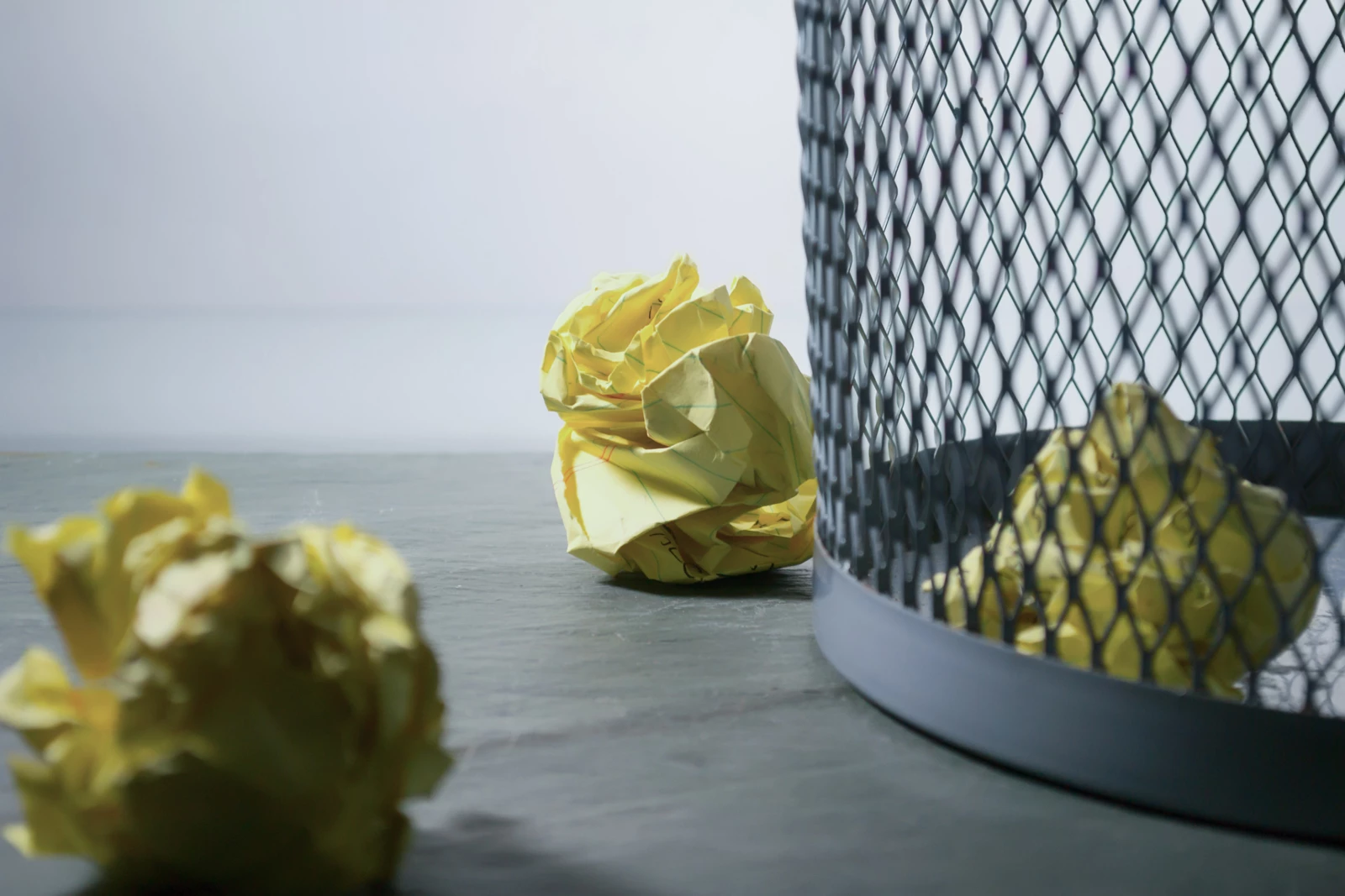 Screwed up waste paper next to a paper bin