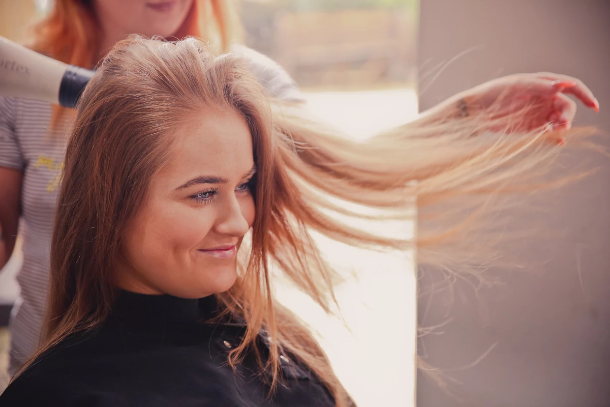 A auburn haired girl having her hair blow dried at a hair salon