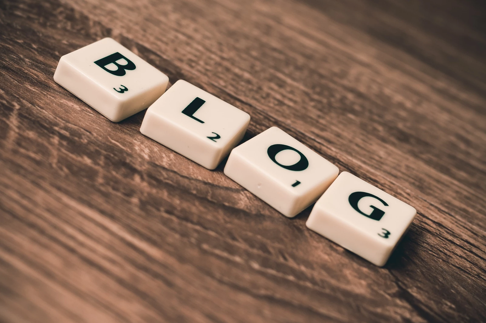 A set of letters on tiles arranged to spell blogs on a wooden table