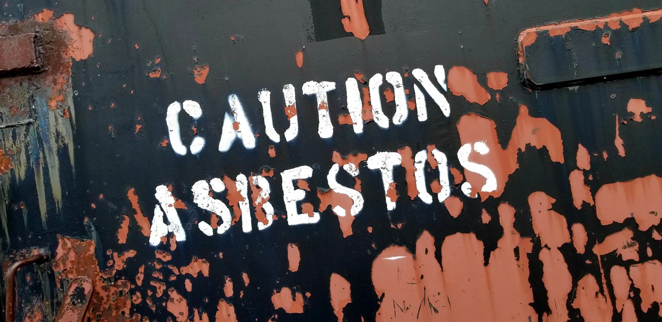A caution asbestos sign on a metal container 