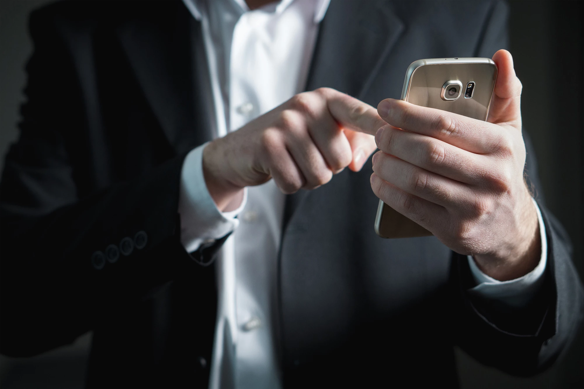 A person in a suit booking a hotel room on their mobile phone