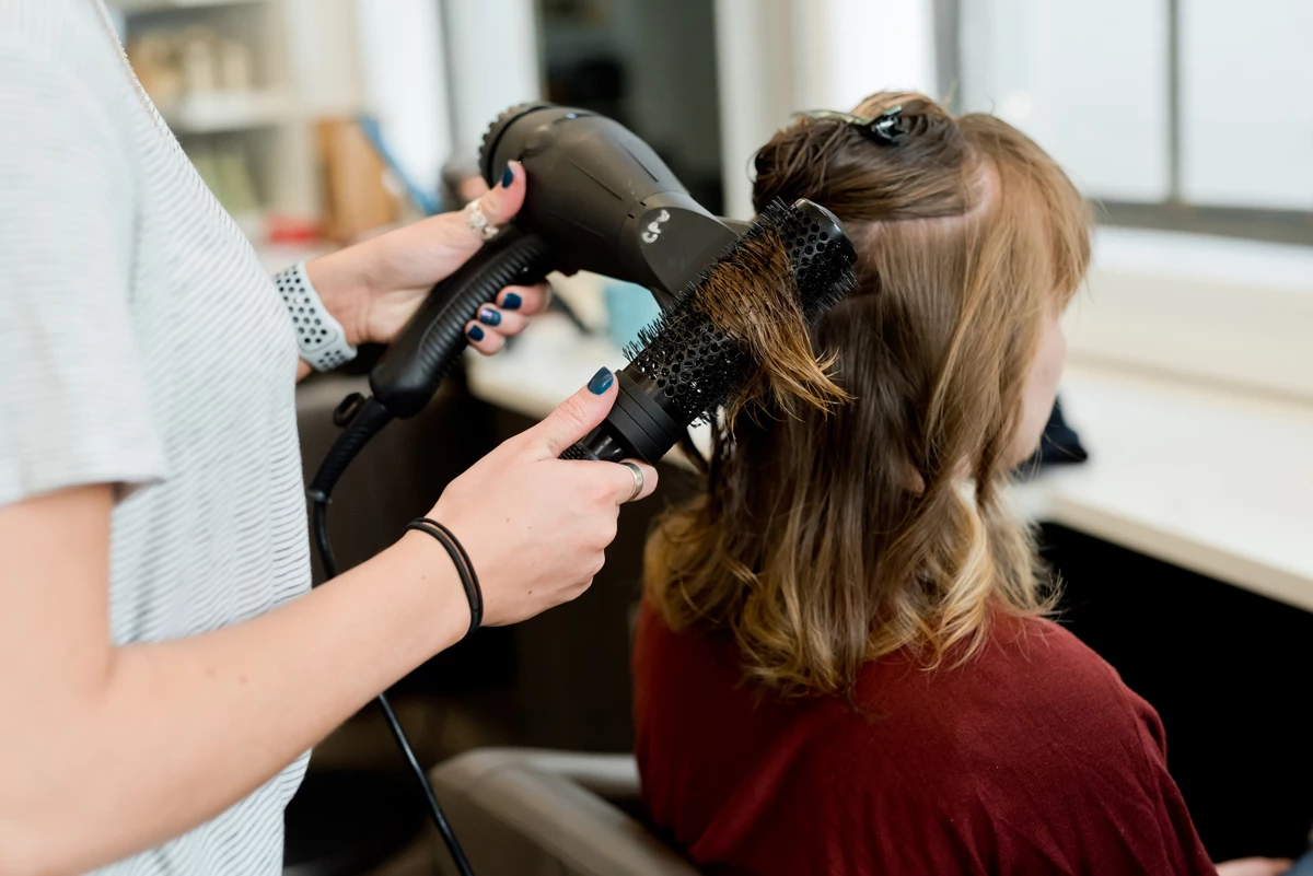 A hair dresser curling a customers hair at a hair salon